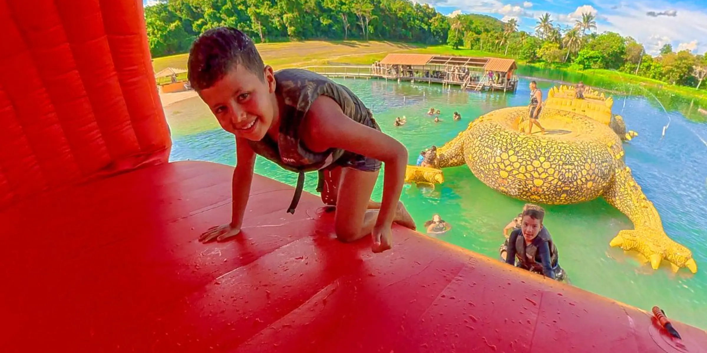 Criança brincando no jacaré inflável do Balneário, com o complexo e o Rio Formoso ao fundo, na Praia da Figueira